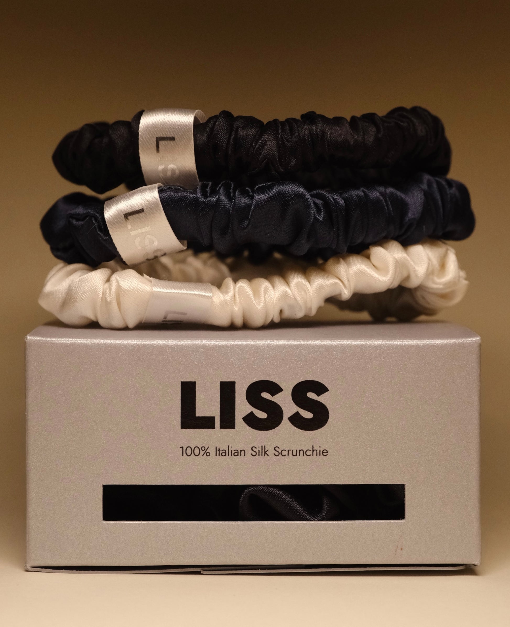 LISS silk scrunchies set in black, navy, and ivory displayed on a LISS branded box