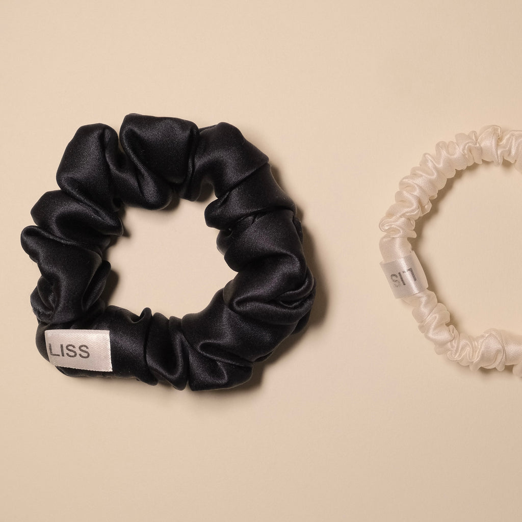 Navy and mini LISS silk scrunchies with logo tags on a beige background